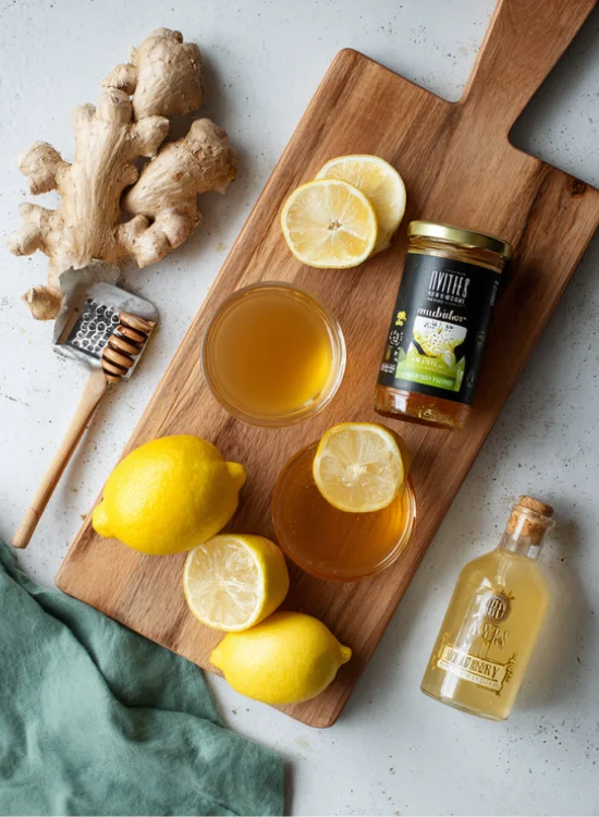 Natural Mounjaro Recipe – A rustic setup with fresh ginger, lemon halves, and honey beside a steaming mug