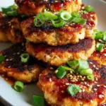 Golden brown Asian tuna cakes seared in a pan and served with fresh greens.