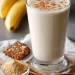 A creamy banana bread protein shake in a glass topped with walnuts and cinnamon