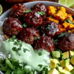 A meal prep container filled with BBQ meatballs, quinoa, steamed broccoli, and a drizzle of green avocado sauce.