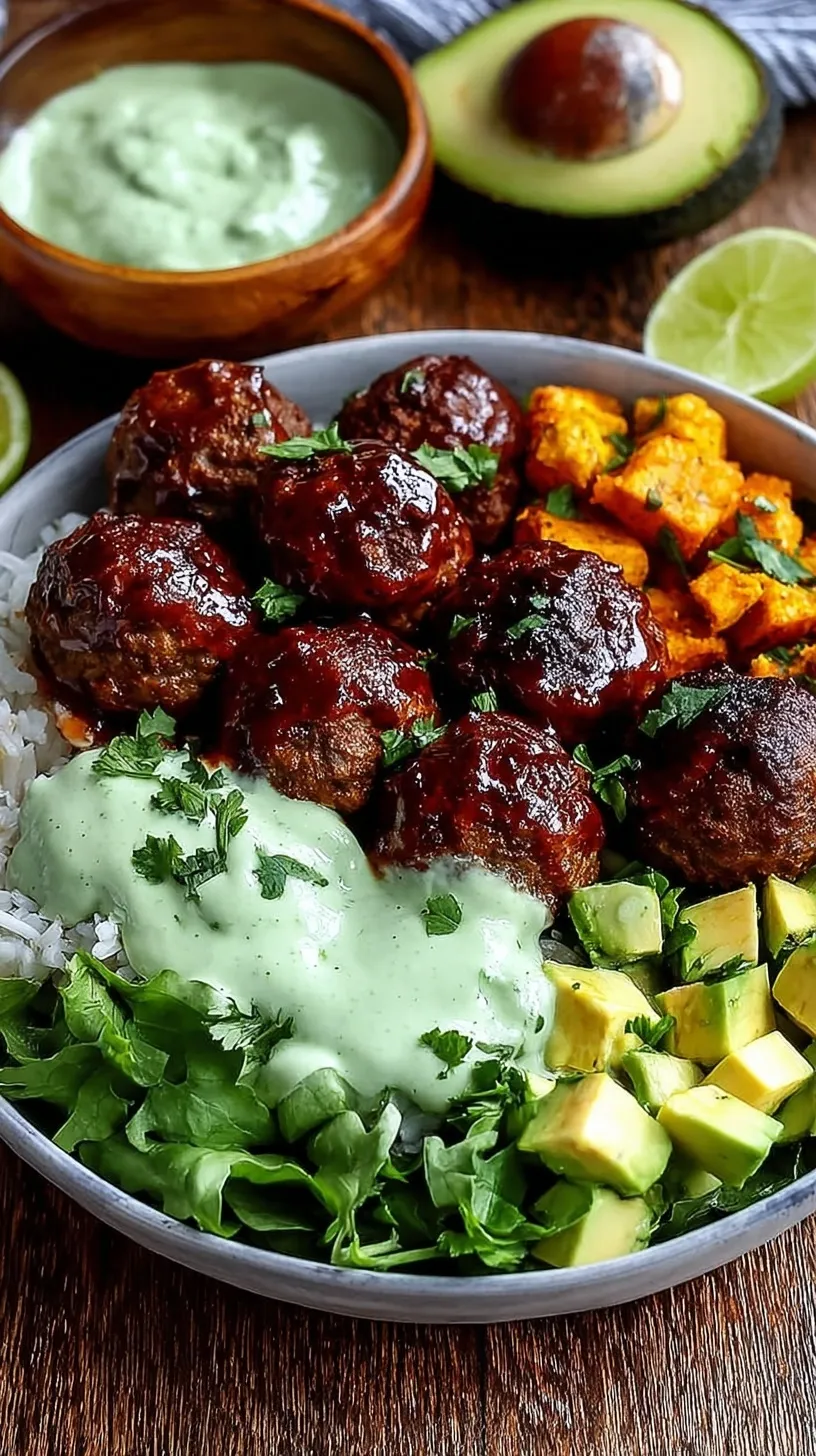 A meal prep container filled with BBQ meatballs, quinoa, steamed broccoli, and a drizzle of green avocado sauce.