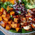 A colorful BBQ chicken sweet potato bowl with roasted potatoes, black beans, and corn.