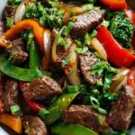 A colorful beef stir fry with broccoli, red peppers, and snap peas in a savory sauce.