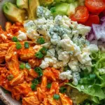 Four meal prep containers filled with buffalo chicken, roasted cauliflower, jasmine rice, and diced celery.