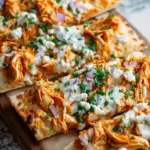 Crispy buffalo chicken flatbread topped with red onions, melted cheese, and a creamy yogurt drizzle