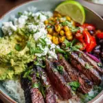 A vibrant bowl with sliced steak, cilantro lime rice, black beans, and roasted corn.
