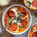 A microwave-safe bowl with melted mozzarella, pepperoni, and marinara over creamy cottage cheese.