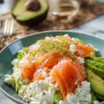 A bowl of creamy cottage cheese salad topped with smoked salmon, avocado, and fresh herbs.