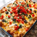A golden, cheesy chicken burrito casserole in a baking dish with layers of tortillas and black beans.