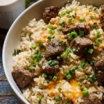 A skillet of savory garlic butter beef rice garnished with fresh green scallions
