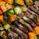 Pan-seared garlic butter steak sliced on a board with roasted brussels sprouts and butternut squash