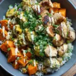 A colorful meal prep bowl with roasted chicken, cubed sweet potatoes, broccoli, and brown rice.