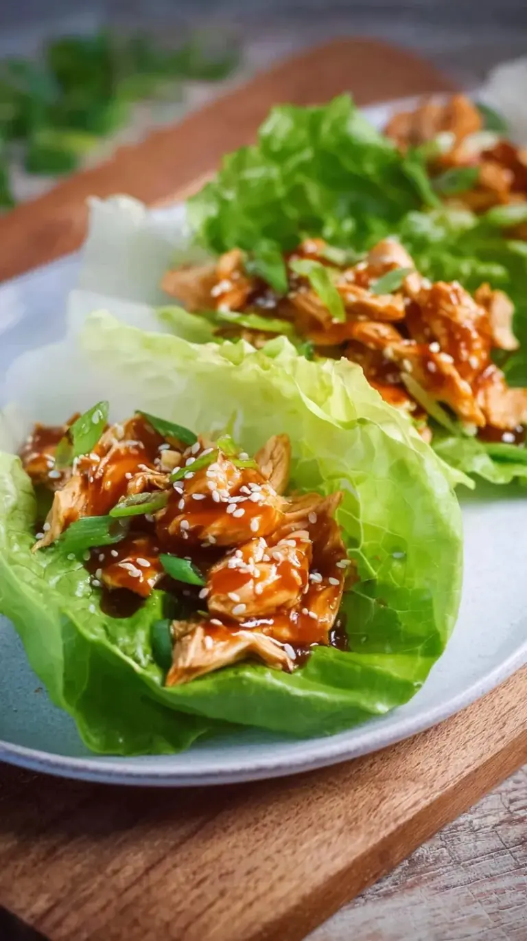 A plate of fresh butter lettuce cups filled with glazed teriyaki ground chicken and topped with sesame seeds.