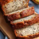 A sliced loaf of golden brown high protein banana bread on a wire cooling rack
