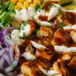 A colorful high protein BBQ chicken bowl with brown rice, black beans, corn, and creamy dressing.