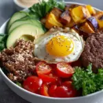 A fresh high protein burger bowl with lean beef, cherry tomatoes, pickles, and creamy sauce in a meal prep container.