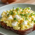 A bowl of creamy cottage cheese egg salad topped with fresh chives and smoked paprika