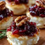 Golden brown cranberry brie bites topped with fresh thyme and honey drizzle in a mini muffin tin.