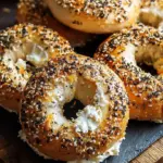 Four golden brown High-Protein Greek Yogurt Bagels topped with everything seasoning on a baking sheet