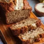 A sliced loaf of golden brown high protein banana bread on a wire rack