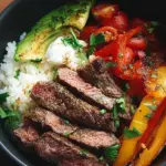 A high protein steak fajita bowl with charred peppers, onions, and quinoa in a meal prep container.