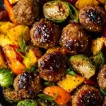 Glazed Korean BBQ meatballs served with roasted broccoli and red bell peppers on a white plate.