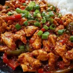 A vibrant skillet of Korean spicy chicken stir fry with golden chicken, green cabbage, and orange carrots.