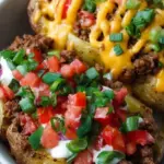 A colorful bowl featuring roasted potato cubes, seasoned ground beef, black beans, avocado, and a dollop of Greek yogurt.