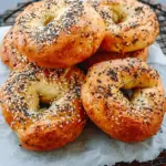 Golden brown air fryer protein bagels topped with everything bagel seasoning on a wire rack.