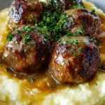 Juicy Salisbury Steak Meatballs smothered in brown mushroom gravy over creamy garlic mashed potatoes