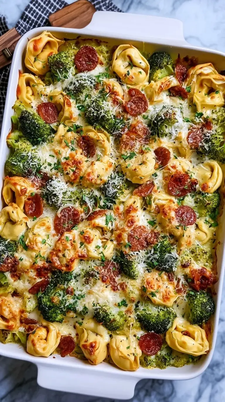 A sheet pan filled with golden roasted cheese tortellini, green broccoli florets, and cubed chicken breast.