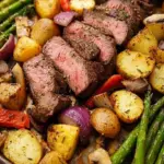 A colorful sheet pan with roasted steak cubes, broccoli, red onions, and bell peppers.
