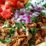 Shredded slow cooker chicken shawarma with charred edges served in a pita with fresh vegetables