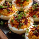 A platter of spicy chili garlic deviled eggs garnished with green scallions and sesame seeds