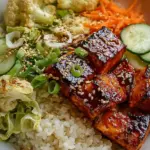 A meal prep container filled with sriracha honey glazed salmon, jasmine rice, and steamed broccoli.