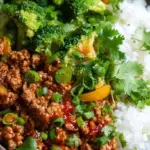 A bowl of jasmine rice topped with glazed ground turkey and bright green broccoli florets garnished with sesame seeds.