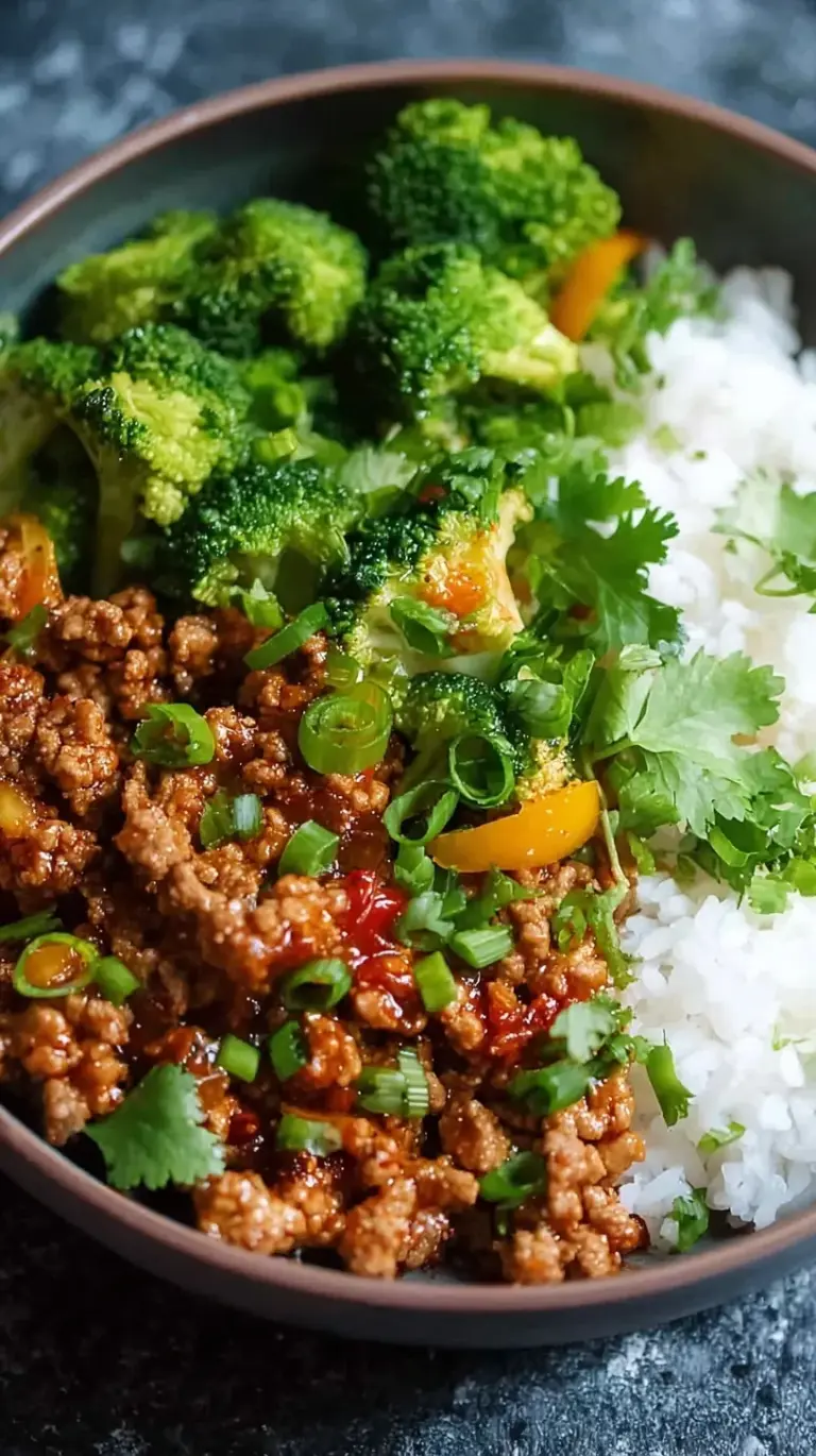 A bowl of jasmine rice topped with glazed ground turkey and bright green broccoli florets garnished with sesame seeds.